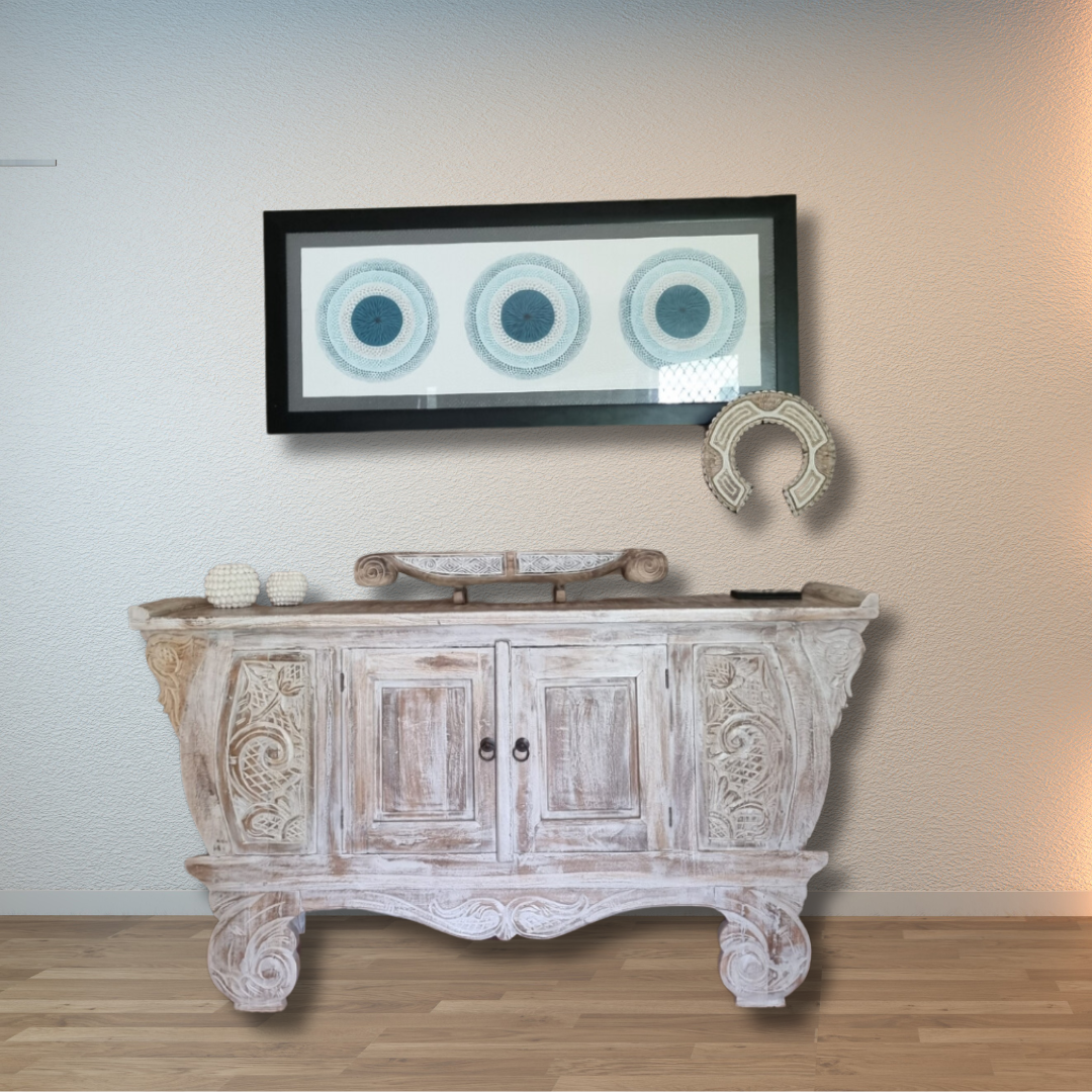 wooden hall way table with intricate carved artwork with additional decorative decor pieces with a painting in the background