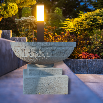 Decorative stone bowl with floral patterns in a garden setting