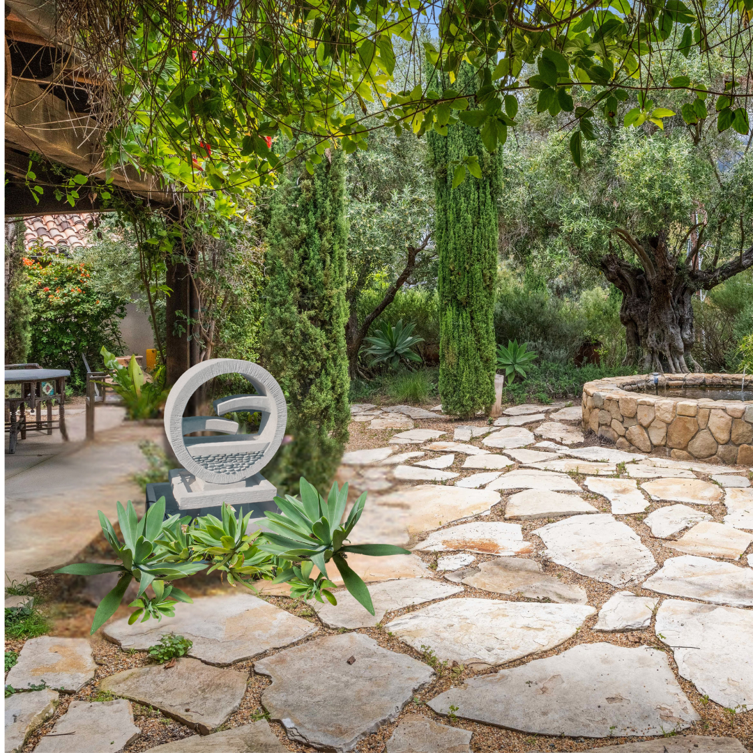 Stone pathway in a garden with a sculpture and trees