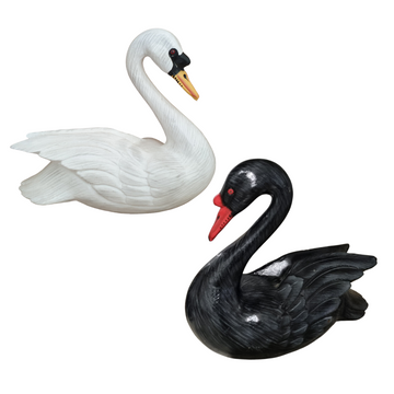 Two wooden carved birds, one in white and one in black, resembling swans with a realistic style.