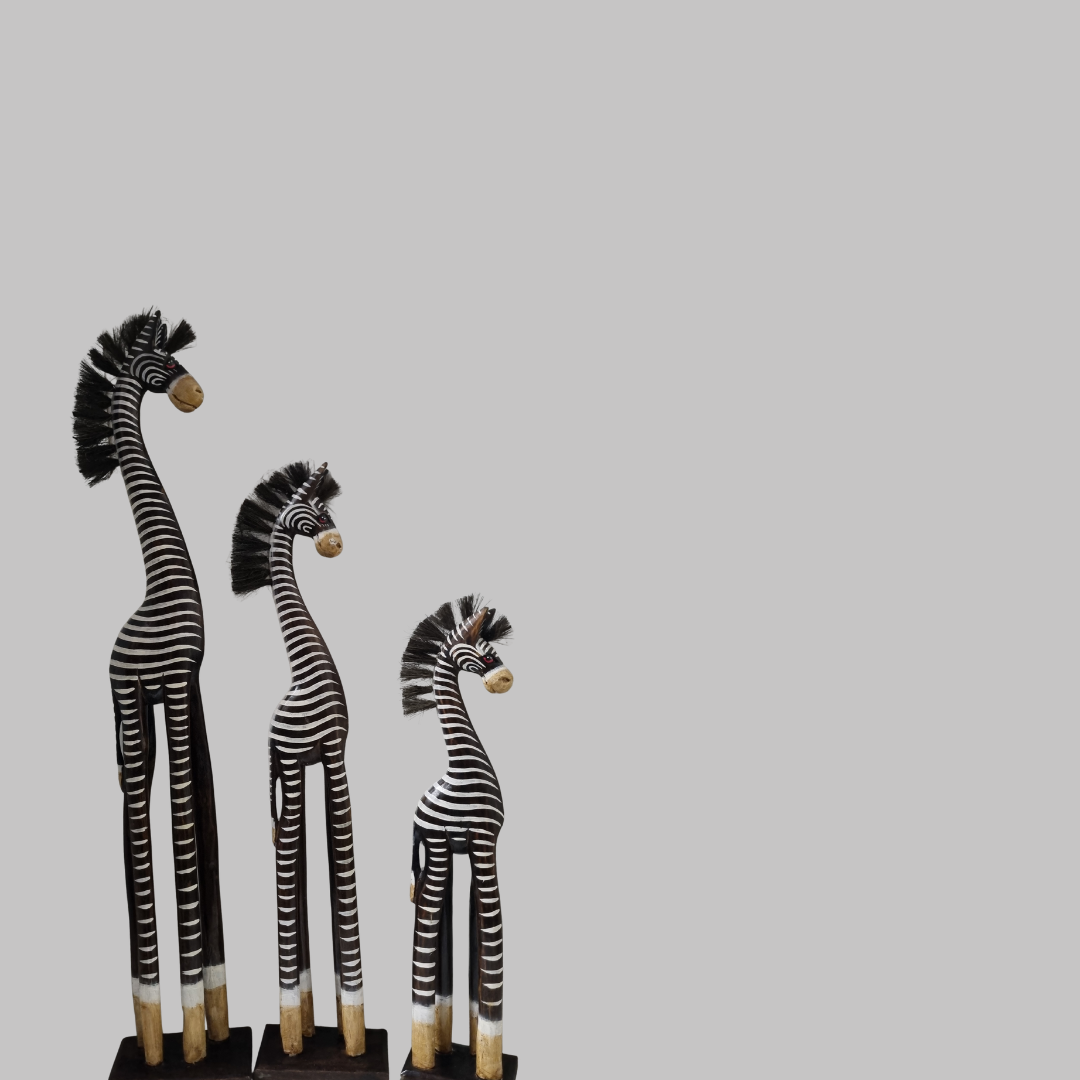 Three zebra figurines of different heights on a plain background