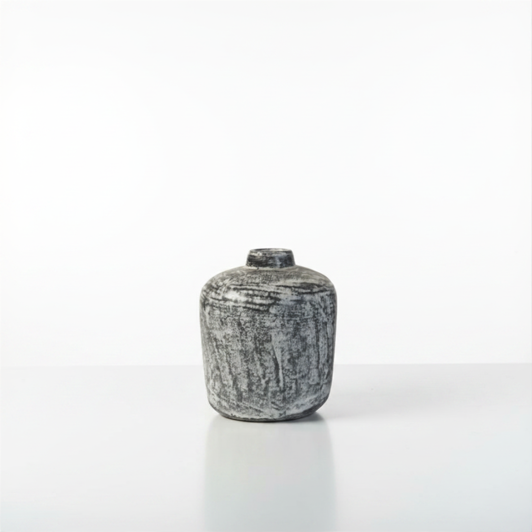 Small squat black wash distressed vase with brushed grey and dark mottled texture on a white background