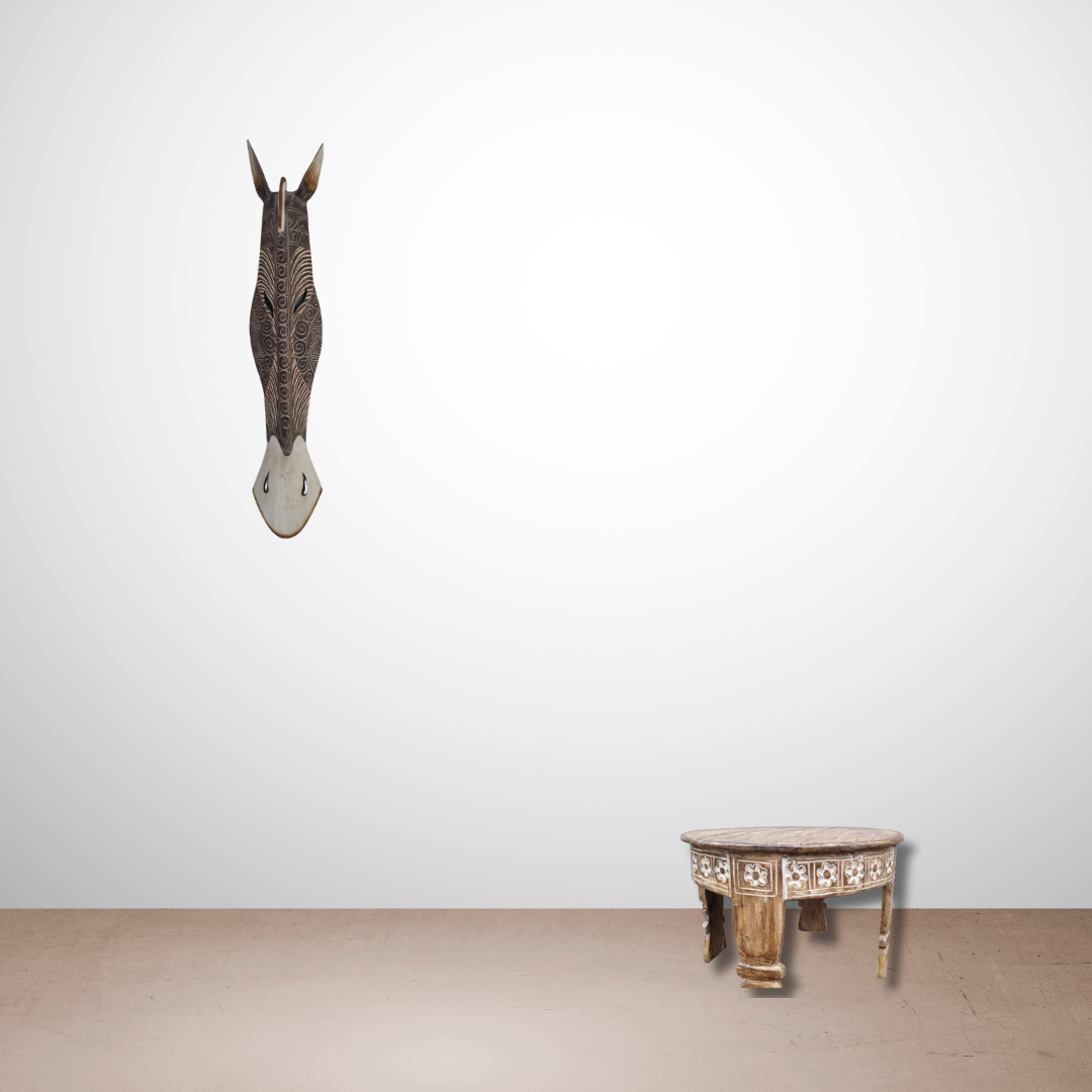 Handcrafted Wooden Giraffe & Zebra Masks Decorative table with intricate designs next to a mounted deer head on a plain white wall.