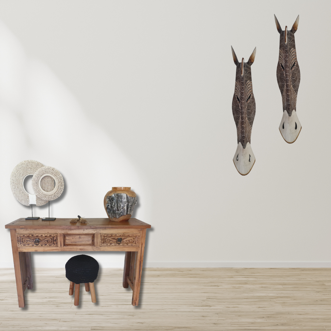 Handcrafted Wooden Giraffe & Zebra Masks Wooden console table with decorative items and two wall-mounted animal heads in a room.