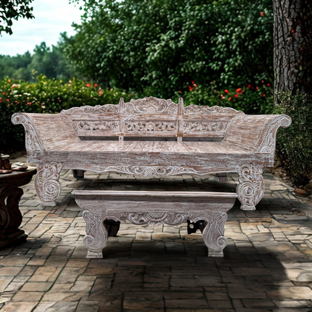 Carved wooden bench in an outdoor setting with greenery.