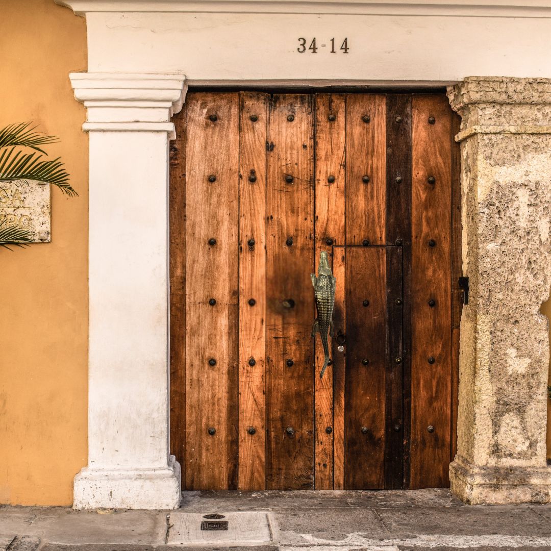 Wooden door with decorative studs on a building facade with number '34-14'.