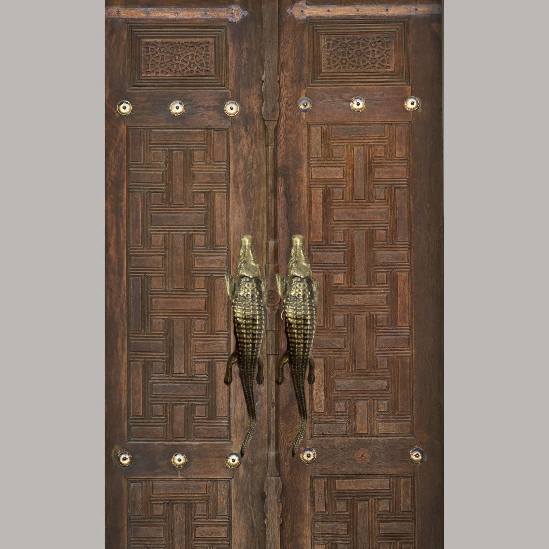 Pair of wooden doors with intricate patterns and decorative handles on a gray background