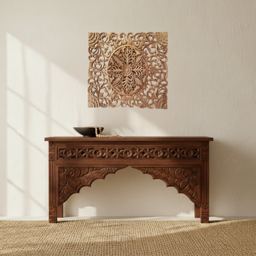 Square floral carved wooden panel above a timber console, styled with pampas grass, a ceramic vase and a woven rug.