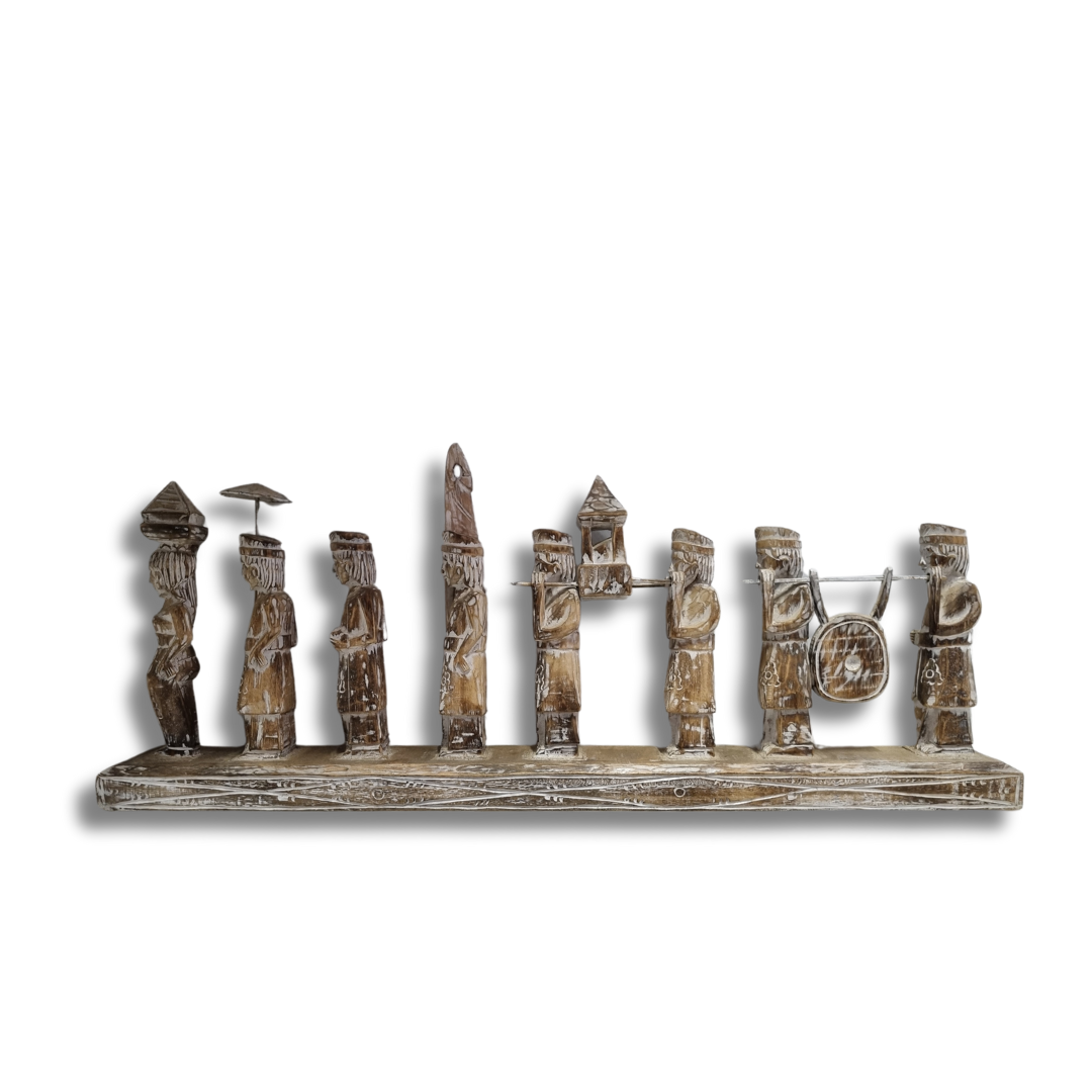 A handcrafted Balinese wooden statue depicting multiple figures in traditional attire, carved in a rustic style with a neutral color palette.