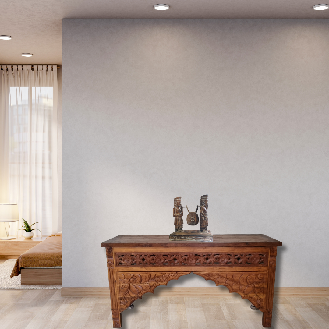 Wooden desk with decorative items in a room with a bed and window.