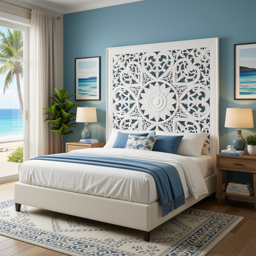 White cut MDF Balinese wall panel behind a king bed in a coastal bedroom with blue walls, ocean view, tropical plants and blue linen accents