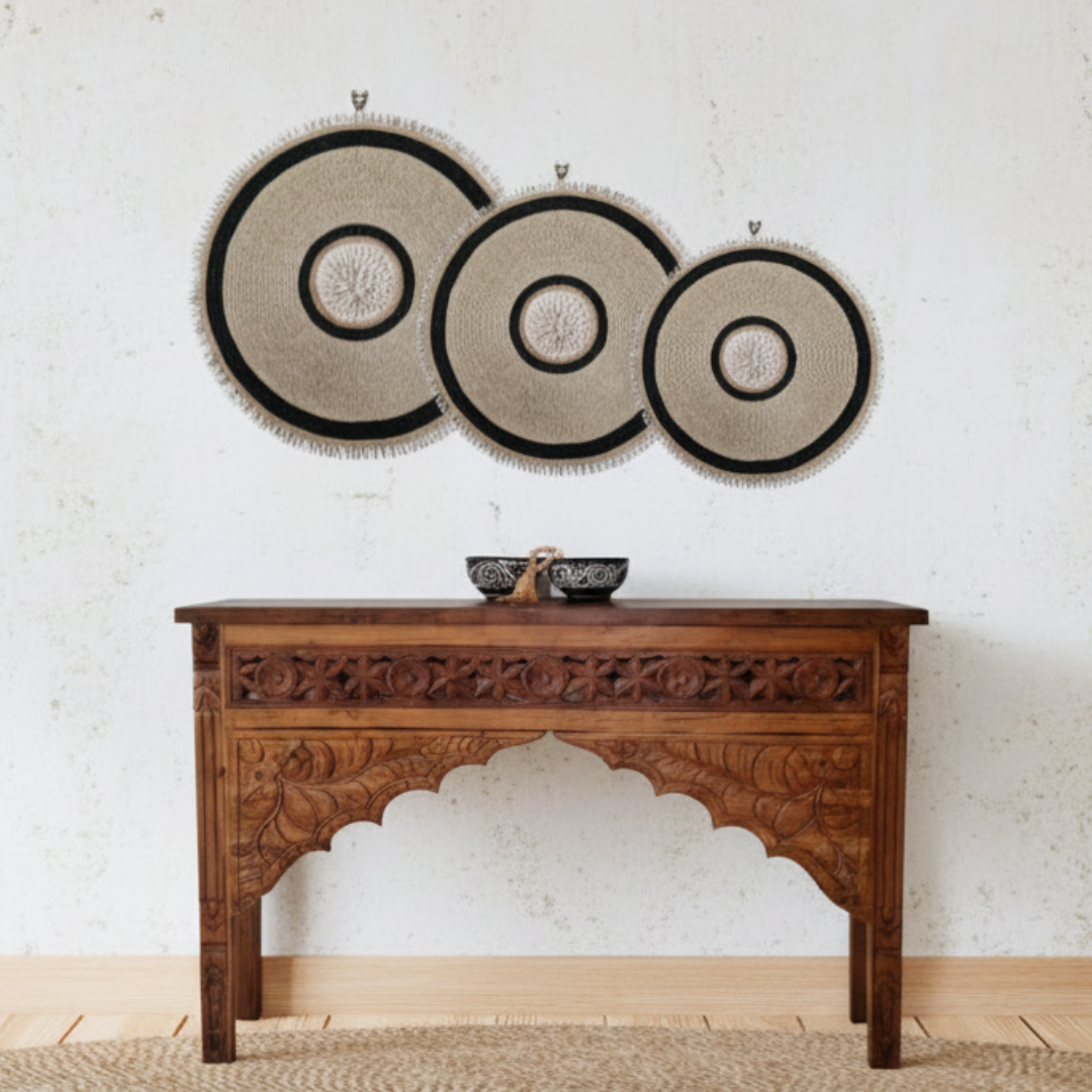 Dark reclaimed teak console table styled against a white wall with woven round wall art and jute rug