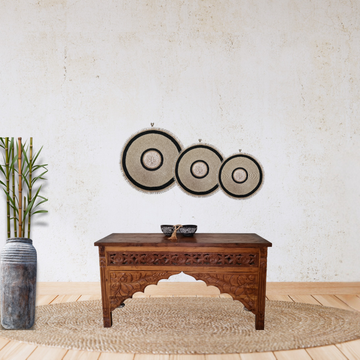 Decorative wall art with circular patterns above a wooden table in a room.