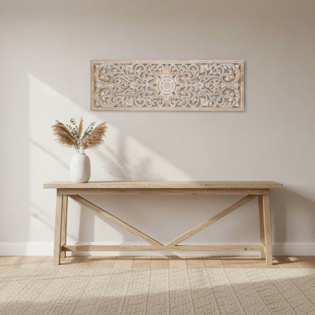 Whitewash precision-cut MDF wall art panel with Balinese floral scroll design hung horizontally above a natural blonde timber cross-brace console table in a bright coastal hallway, styled with a white ceramic vase of dried pampas grass and eucalyptus