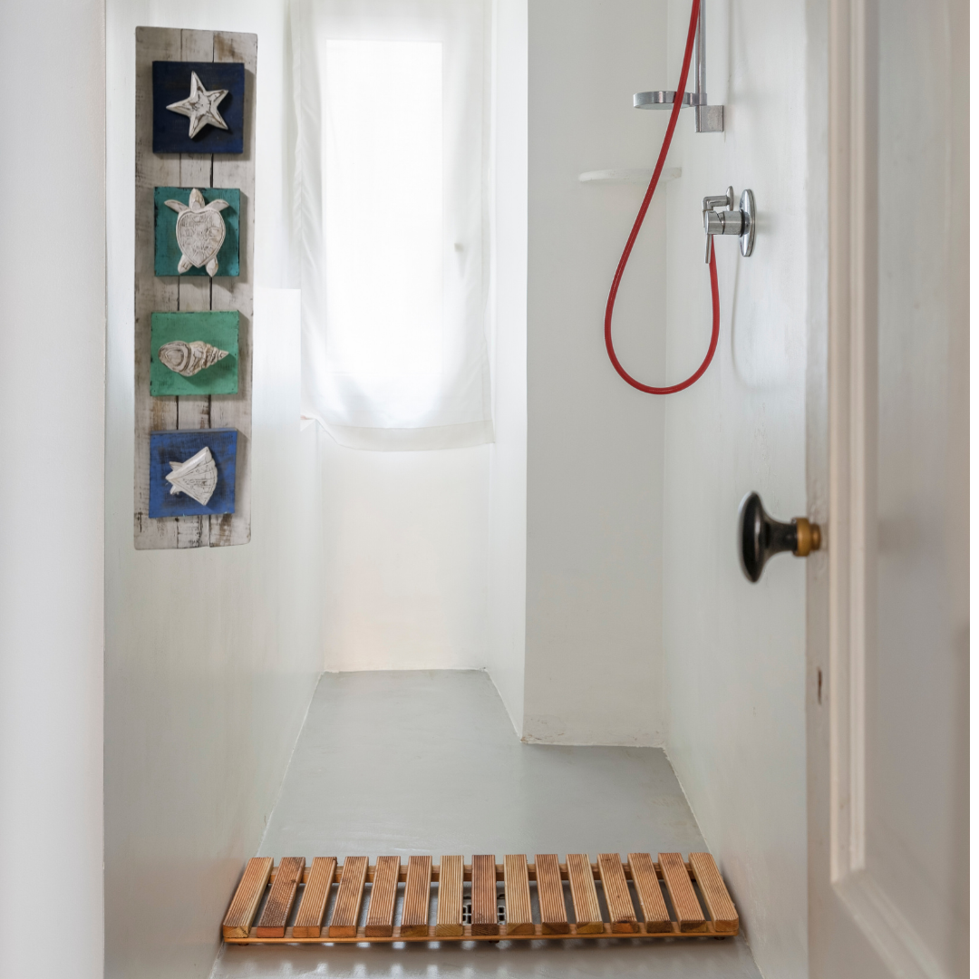 bathroom with a nauticle style wooden wall art hanging with wood carvings to suit beachy style home. in a casual shower bathroom areas. 