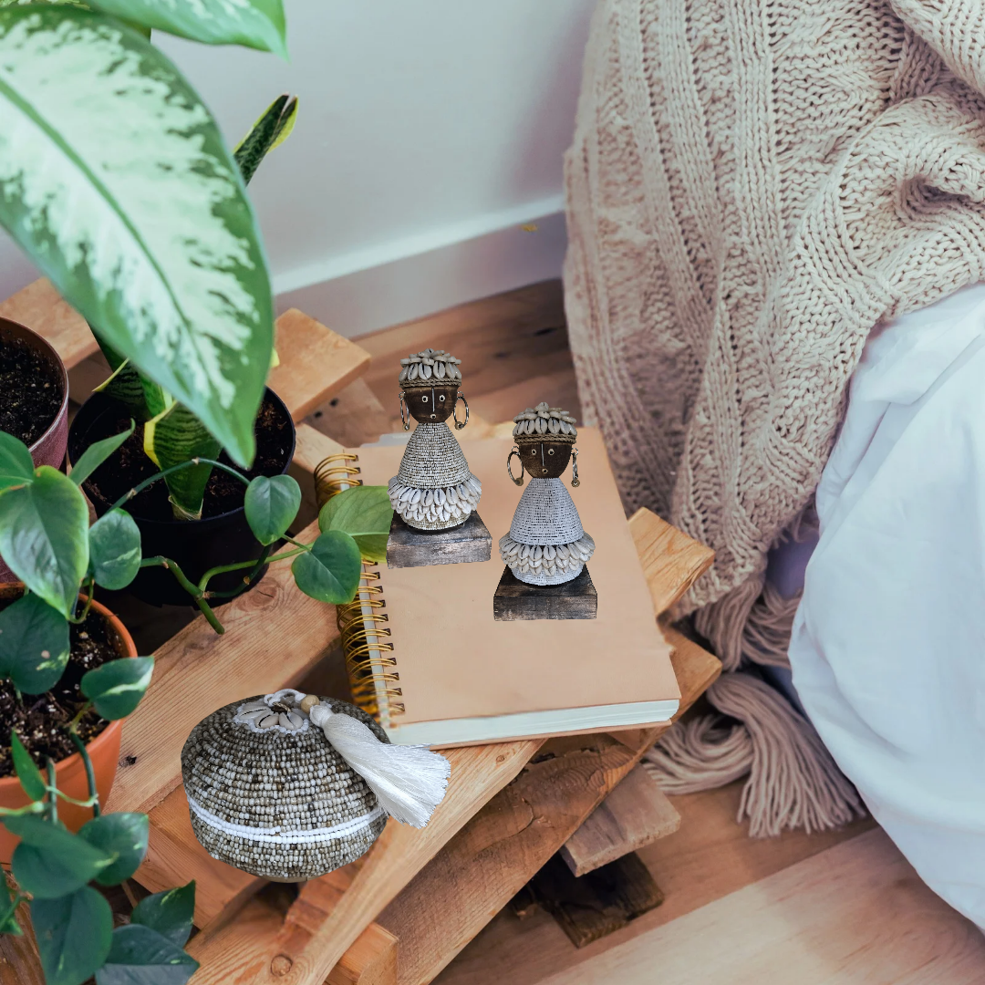 Small wooden table with decorative items including a notebook, small statues, and a plant on a wooden floor.