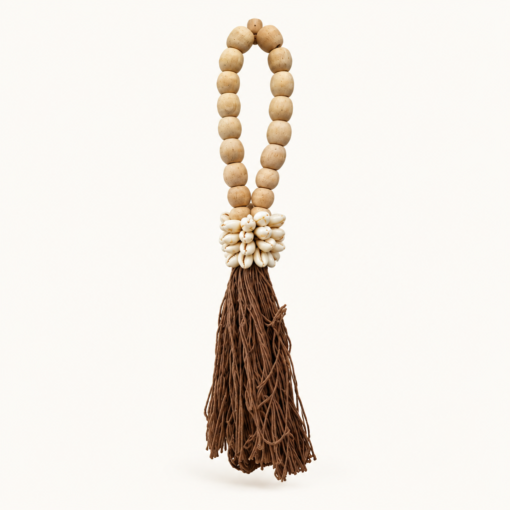 Brown cotton strands below an oval wooden loop and a cluster of cowrie shells