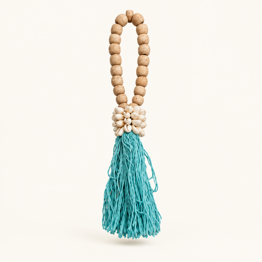 Turquoise cotton strands below an oval wooden loop and a cluster of cowrie shells