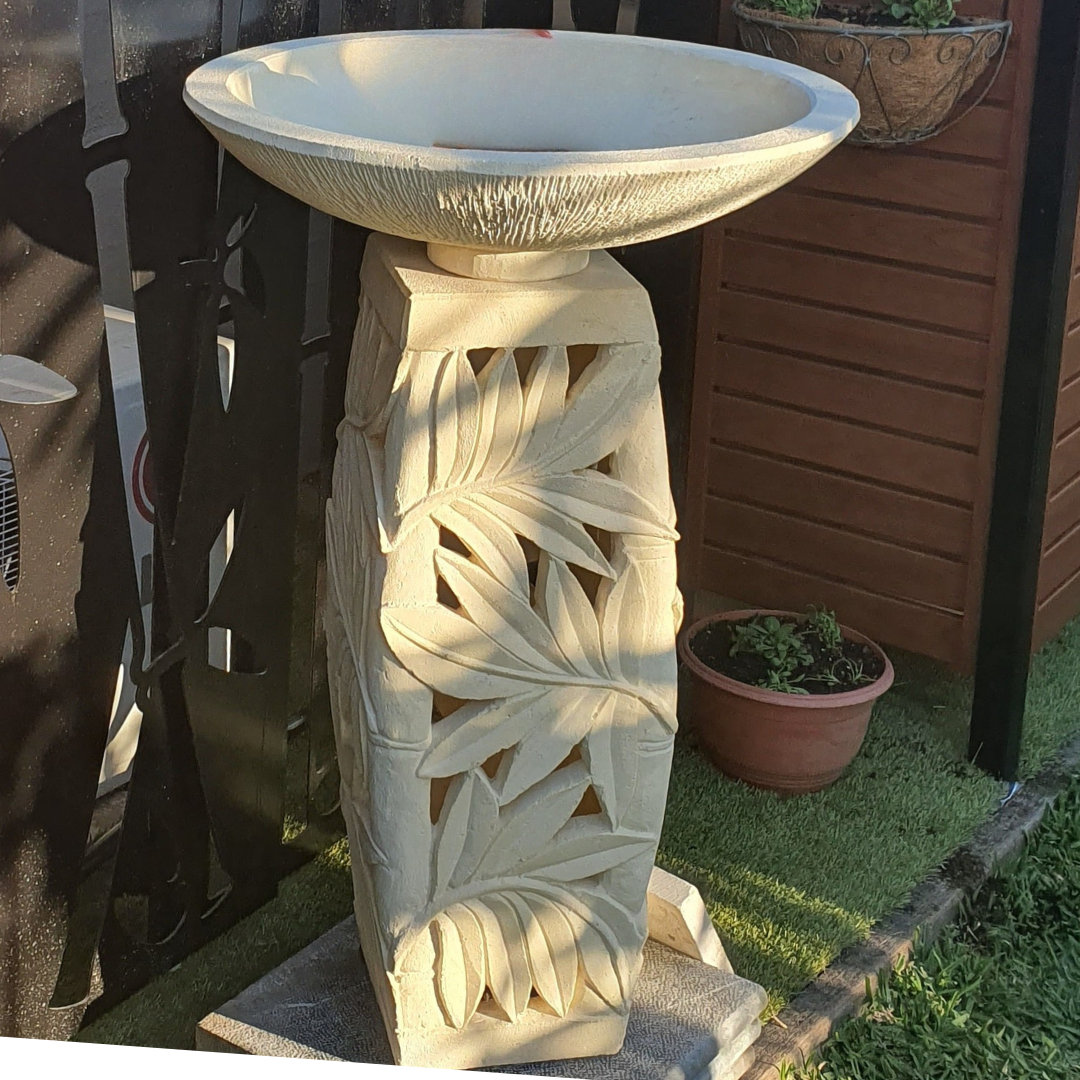Concrete pedestal with leaf carving, outdoor setting, green lawn and terracotta pot
