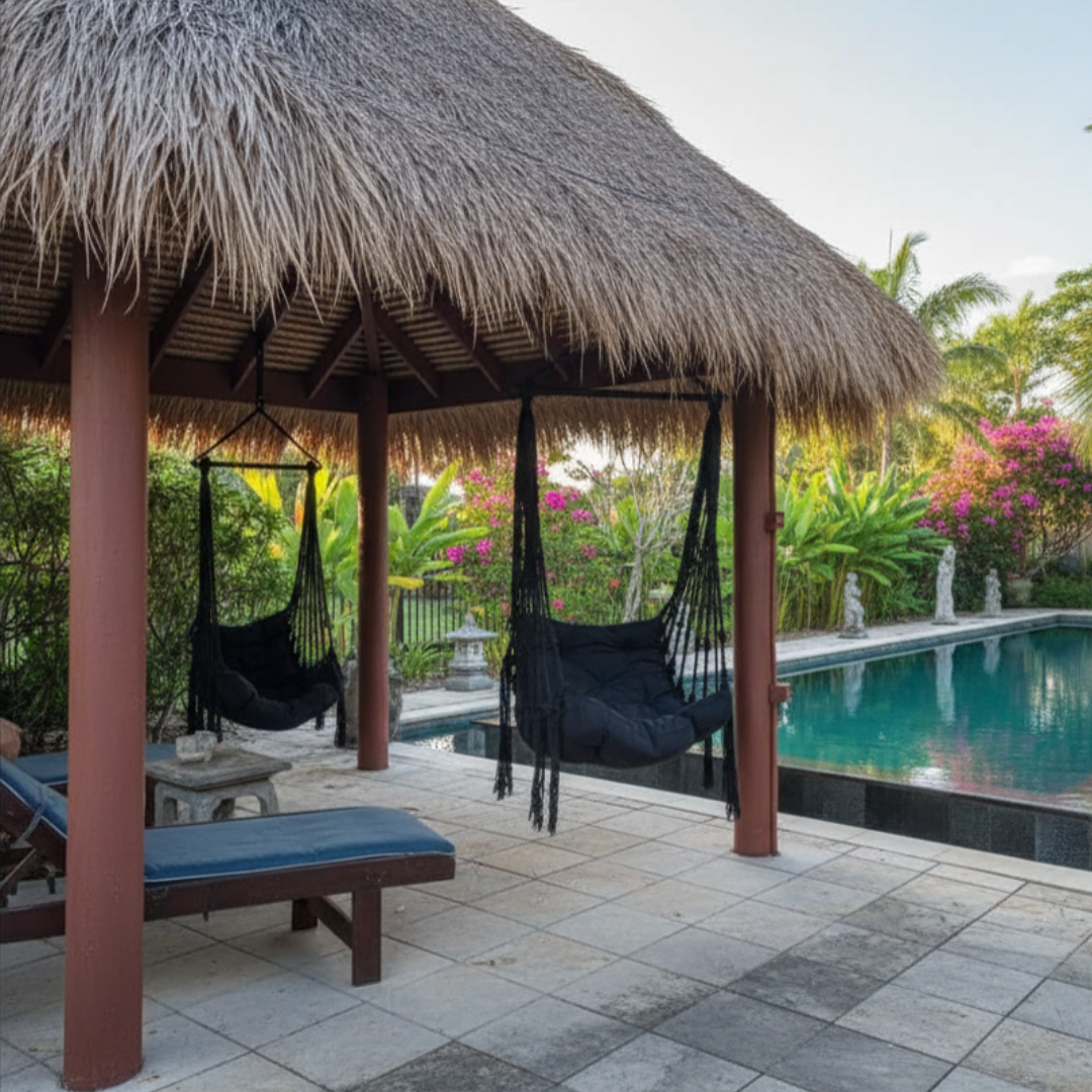 Thatched-roof gazebo with hammocks by a poolside in a tropical setting