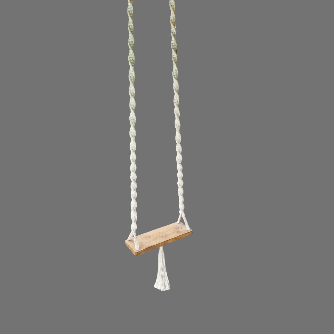 A handcrafted Balinese style white macrame swing with a solid wooden seat, designed with intricate patterns and tassels.