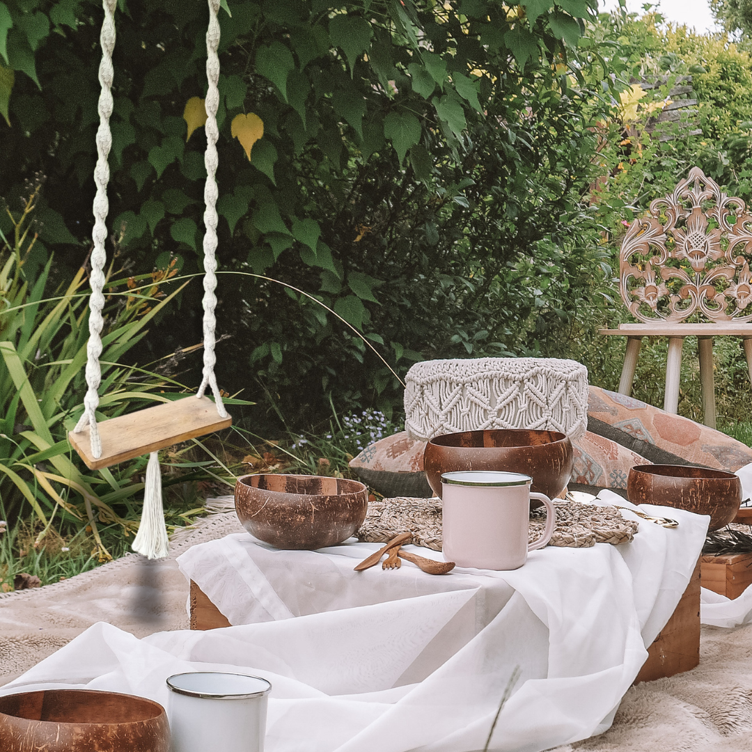 A handcrafted Balinese style white macrame swing with a solid wooden seat, designed with intricate patterns and tassels.
