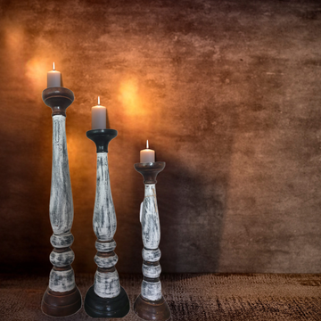 Three candle holders with candles on a textured brown surface