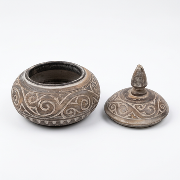 studio shot of opened carved contain with lid beside it 