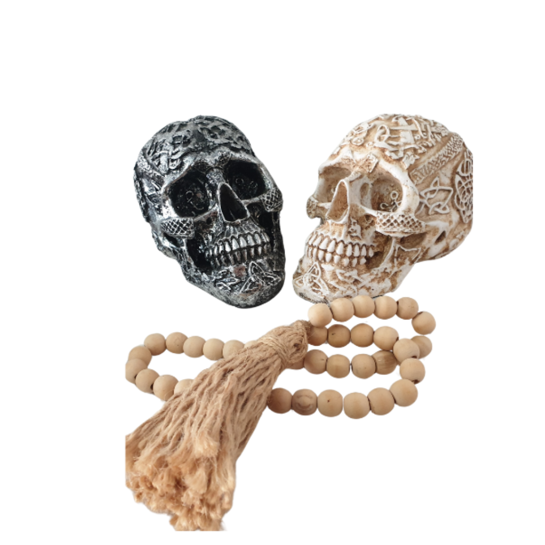 Boho Skull Art Tabletop Design in Silver and White/Cream, handcrafted resin human skulls with intricate Celtic and floral detailing, styled with natural wooden bead garland and tassel, 17cm x 12cm x 11cm décor pieces by Azure Decor