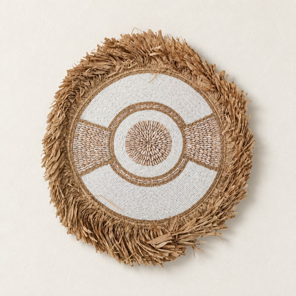 boho style shield wall art, Circular wall hanging with shell centre and straw fringe against a warm white wall