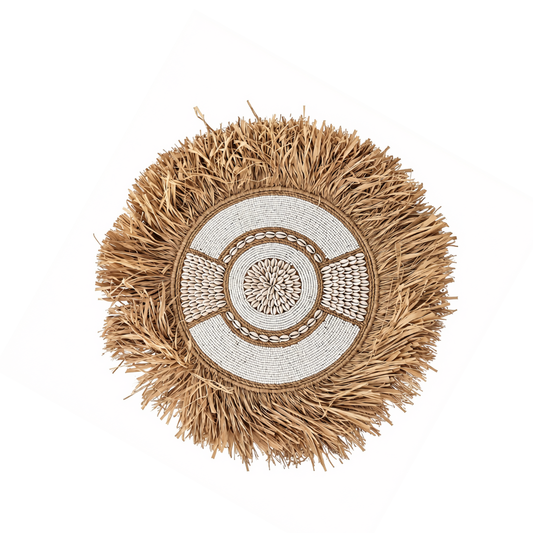 A round woven decorative pillow or wall hanging with a natural straw fringe around a cream and tan geometric center panel, shown on a plain white background.