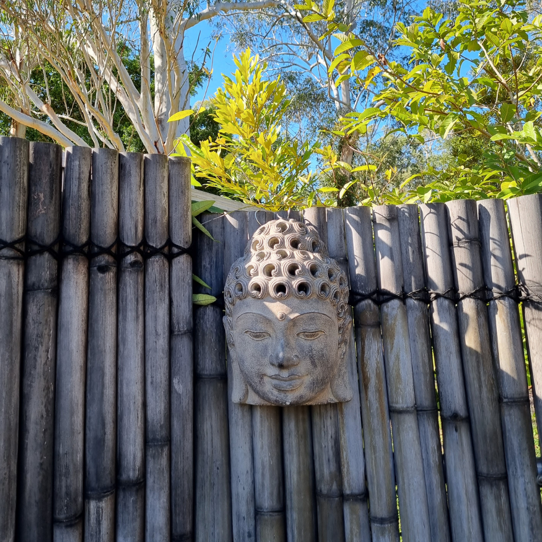 buddha face set on bamboo fence with greenery 