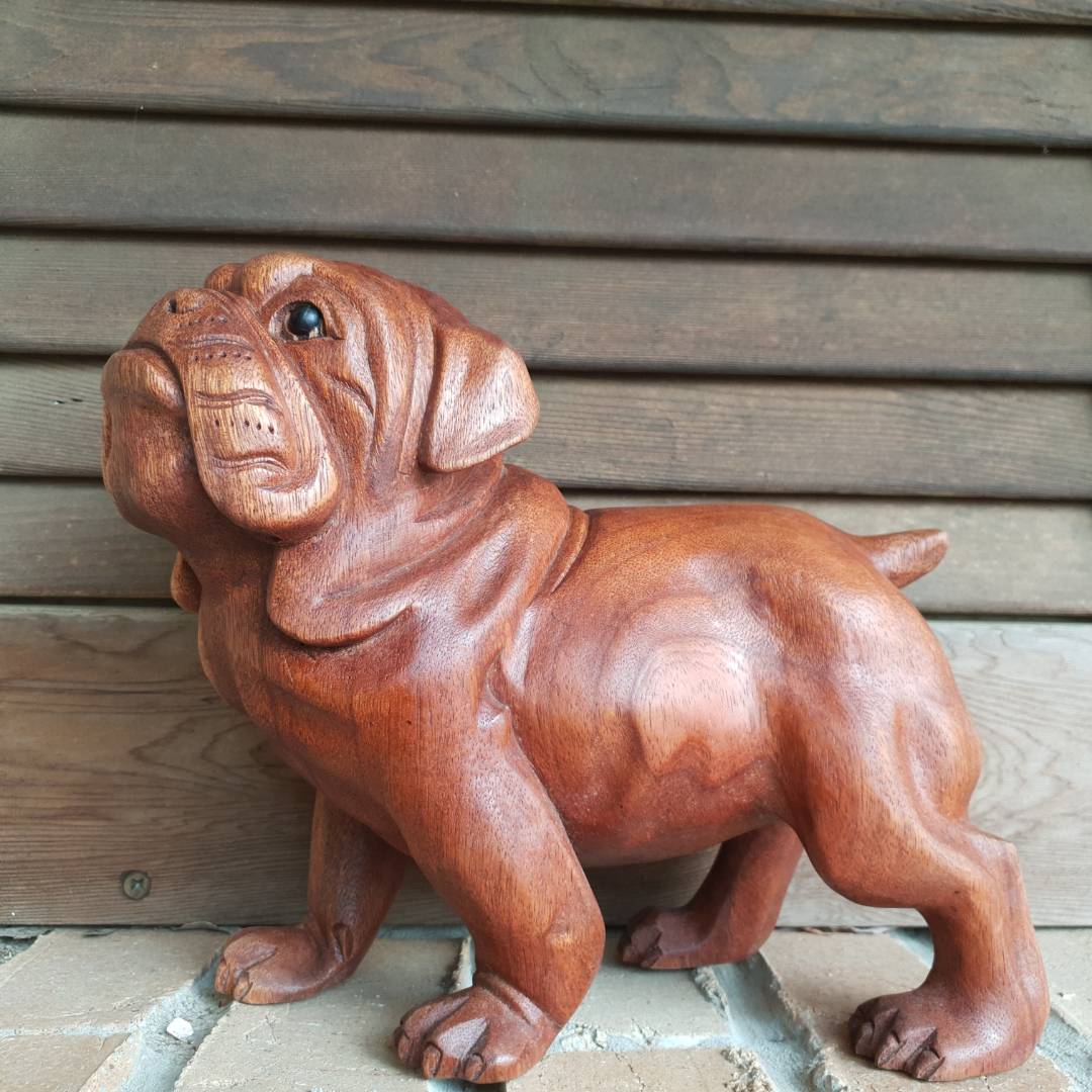 Bull Dog Wooden Carving displayed on paving in front of horizontal timber boards.