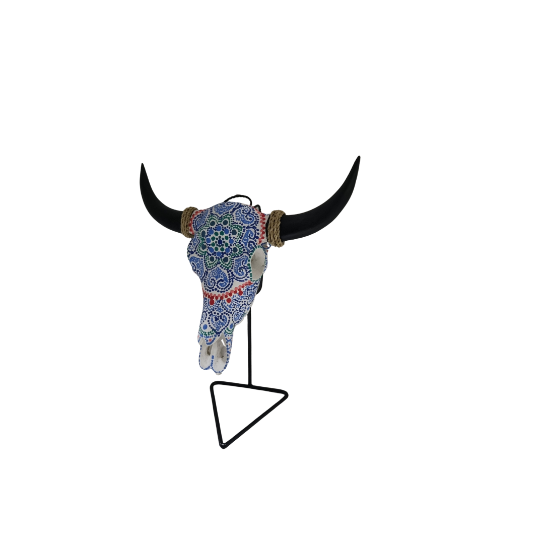 Azure Mandala Bull Skull – hand-painted resin bull skull with intricate blue and white dot mandala lace pattern and red dot border, black horns with jute rope wraps on black metal triangle stand, white background