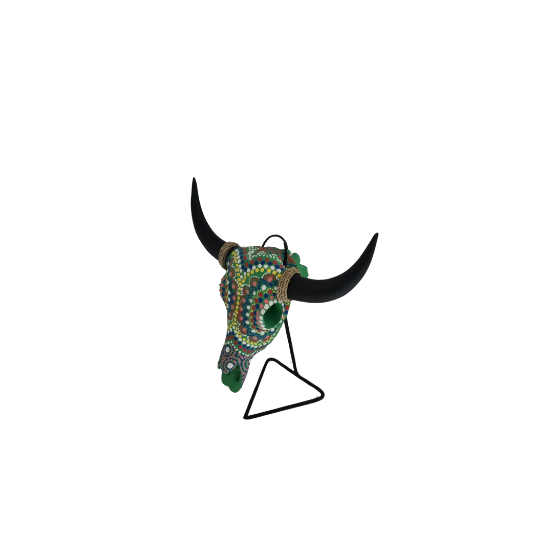 Green Goddess Skull – hand-painted resin bull skull with vibrant multicolour dot mandala pattern in green, pink, red and yellow with green floral accents and jute rope horn wraps on black metal triangle stand, white background