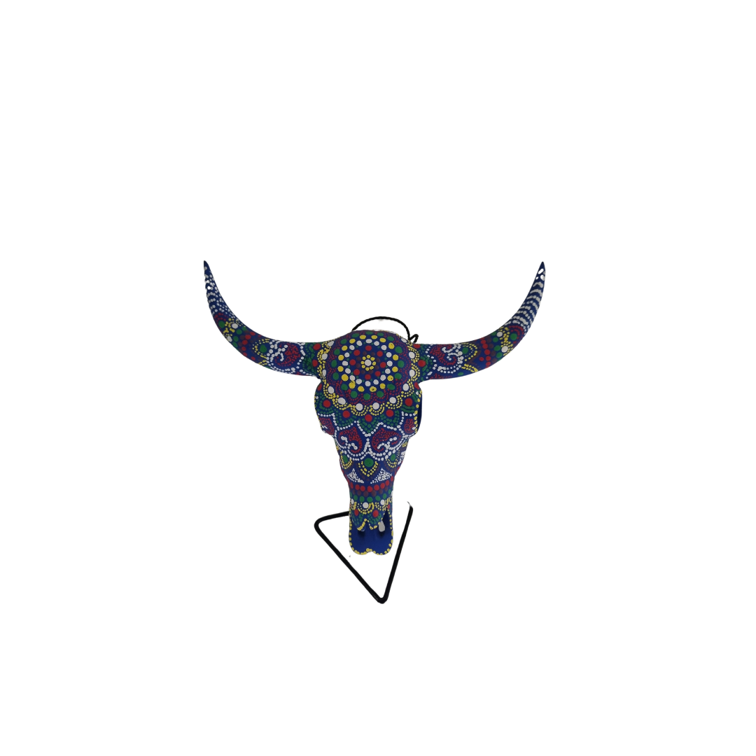 Mystic Mandala Bull Skull – hand-painted resin bull skull with vibrant multicolour dot mandala pattern in deep blue, purple, red and yellow covering skull and horns, with hanging cord on black metal triangle stand, white background