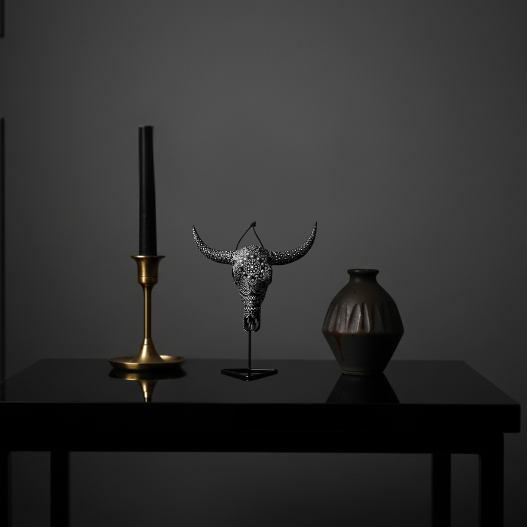 Nocturnal Mandala Skull – black and silver-grey dot mandala resin bull skull on black metal stand styled on a dark marble side table in a sophisticated moody interior with black candle and dramatic lighting
