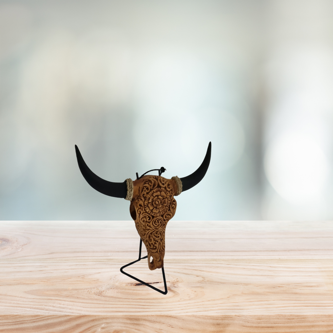Celestial Flora Skull – hand-painted resin bull skull with intricate warm brown floral scroll pattern on black metal triangle stand, white background