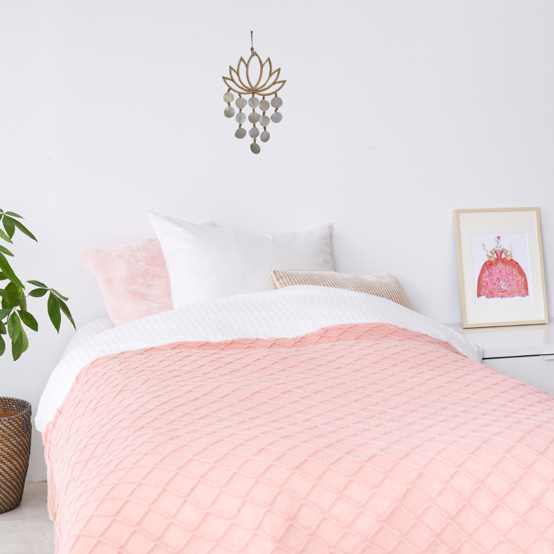Bedroom with pink quilt, white pillows, and decorative wall art.