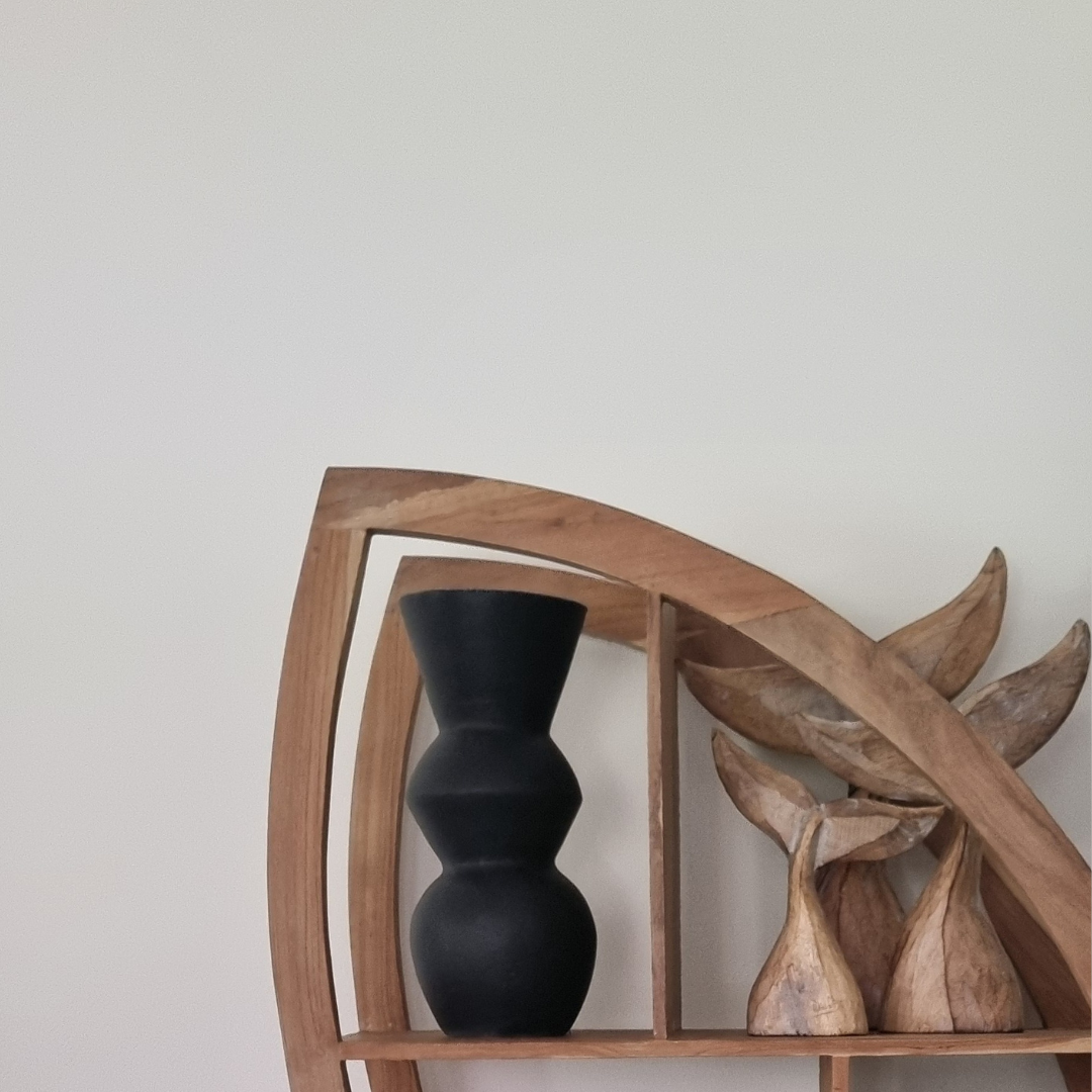 Black vase on a wooden shelf with natural wood decor