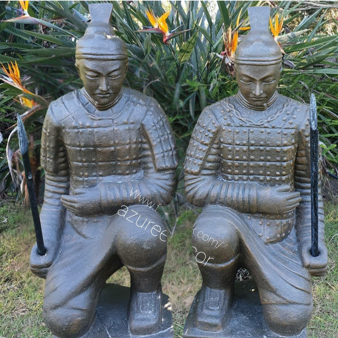 china warrior statues in front of a green garden 