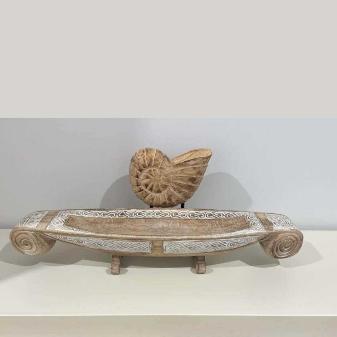 Hand-carved wooden nautilus shell on black stand styled on a white shelf with a Balinese carved timber tray – coastal and Hamptons home decor styling by Azure Decor