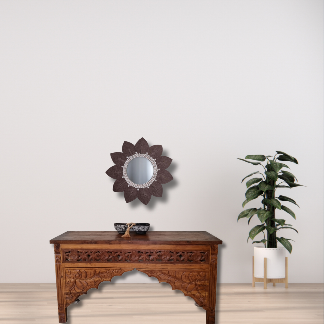 Brown macramé leaf wall mirror with white shell bead surround – handcrafted boho coastal décor Australia Wooden console table with decorative mirror and plant against a plain wall