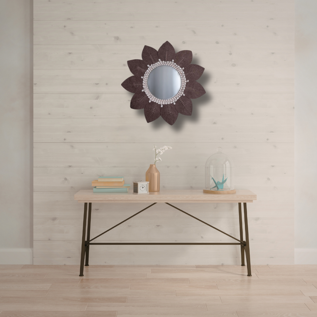 Decorative mirror with floral design on a wall above a wooden table.