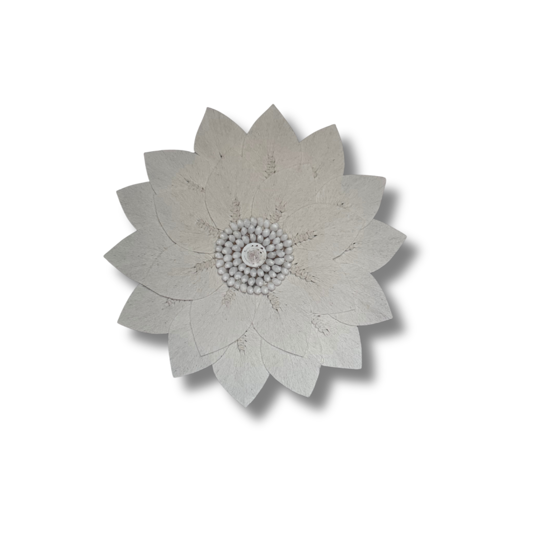 Decorative macrame wall piece with a floral and shell design on a white background