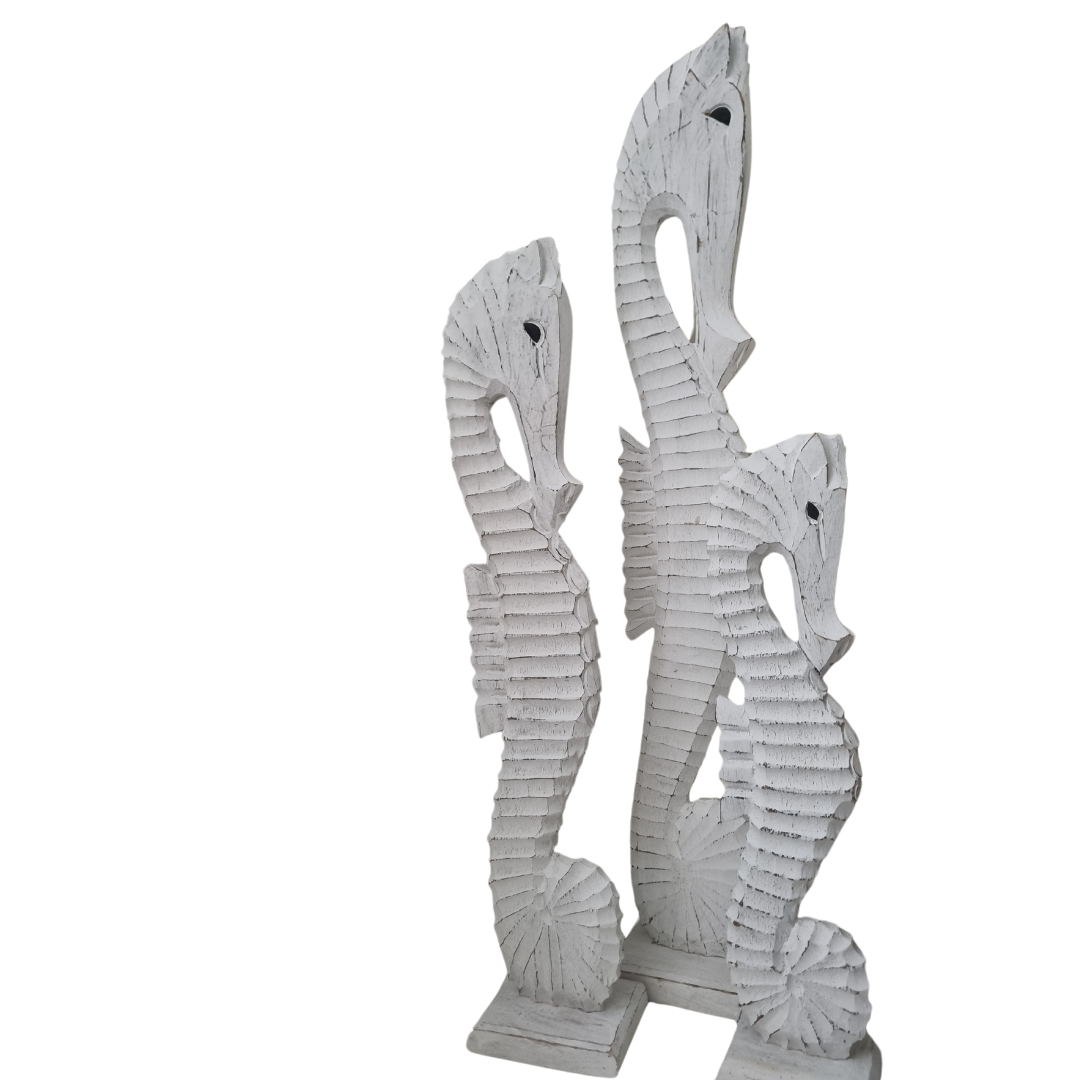 Sea horse statues large medium and small in size on a white back wall 
