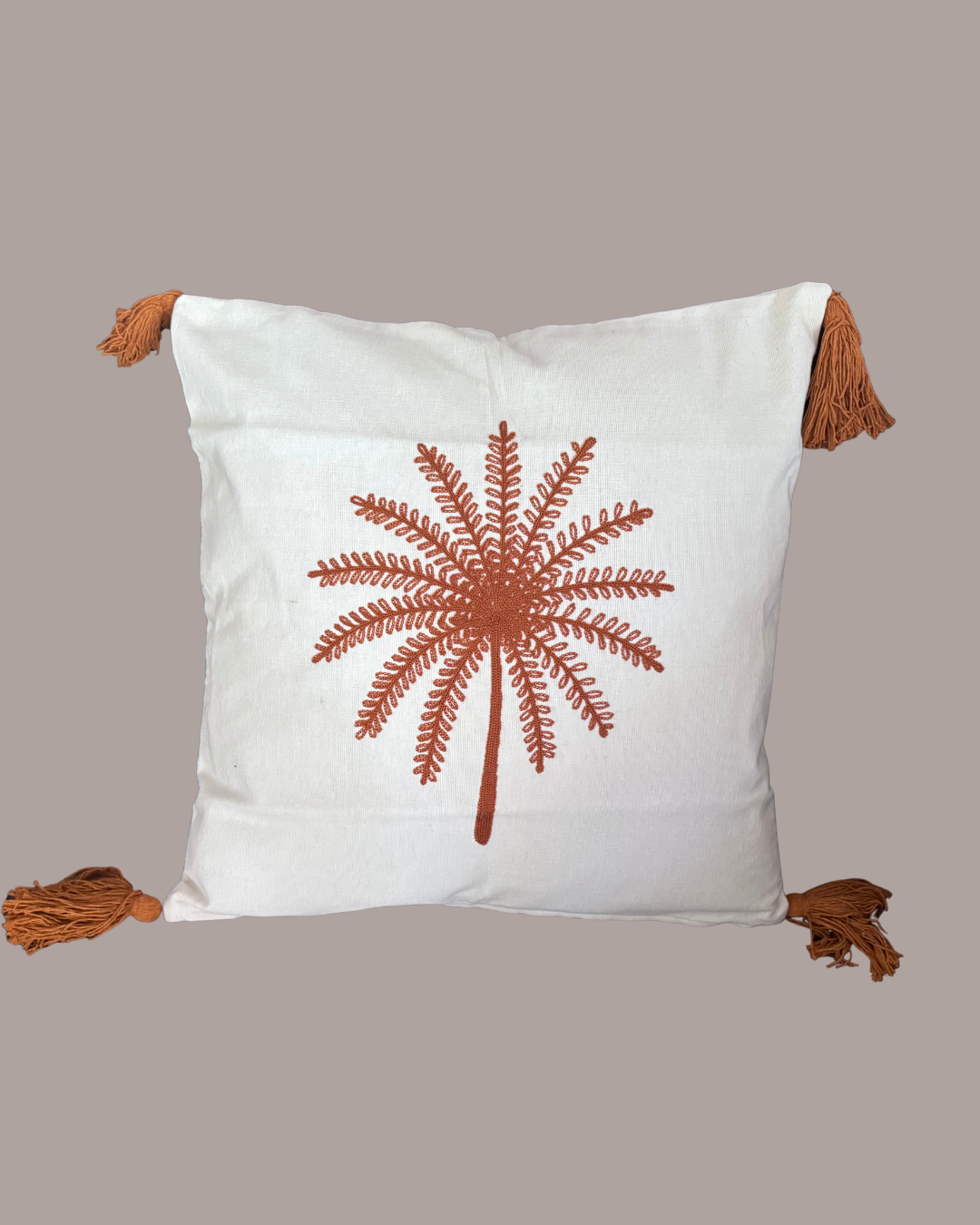 Decorative pillow with a brown floral design and tassels on a beige background