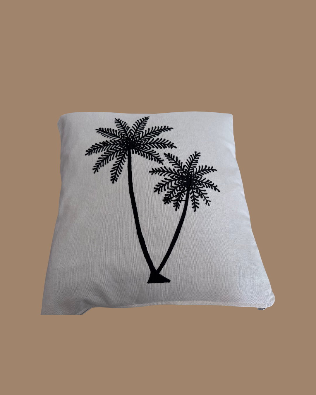 Gray pillow with black palm tree design on a brown background
