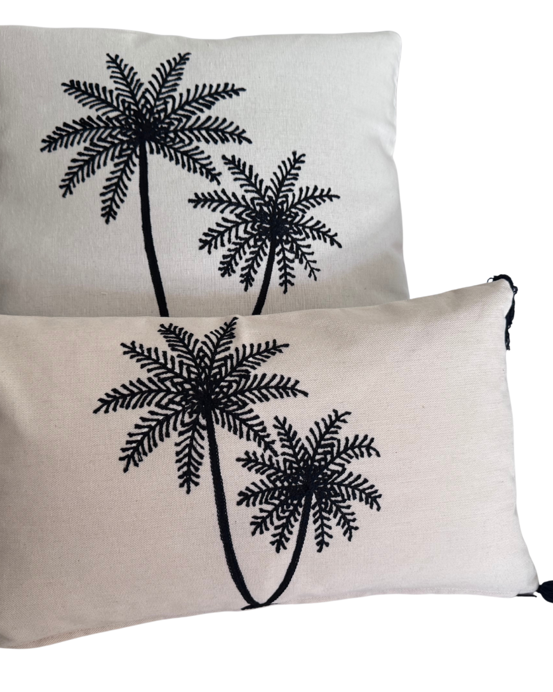 Two pillows with black palm tree designs on a white background