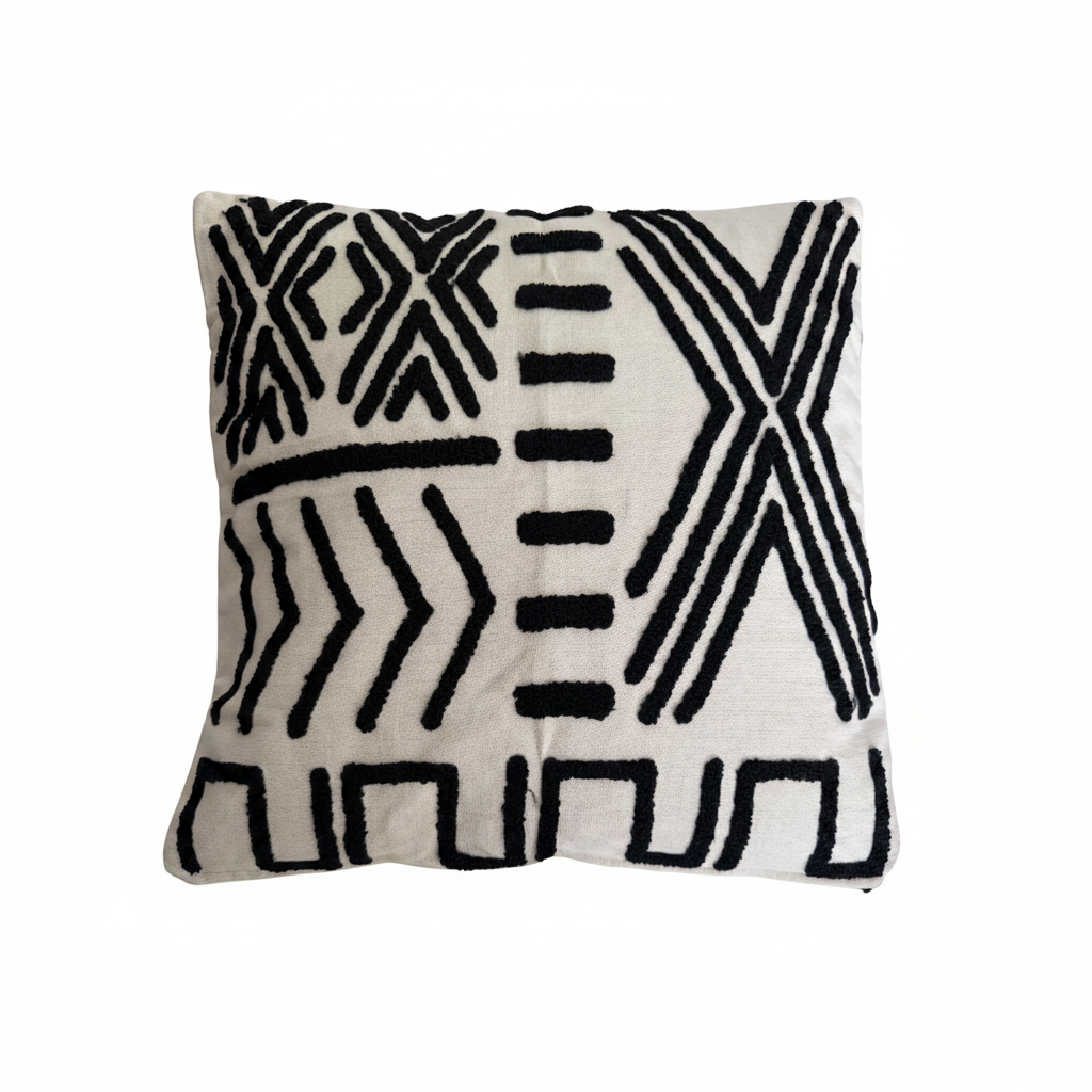 White geometric embroidered cushion styled on a natural linen sofa in a coastal living room
